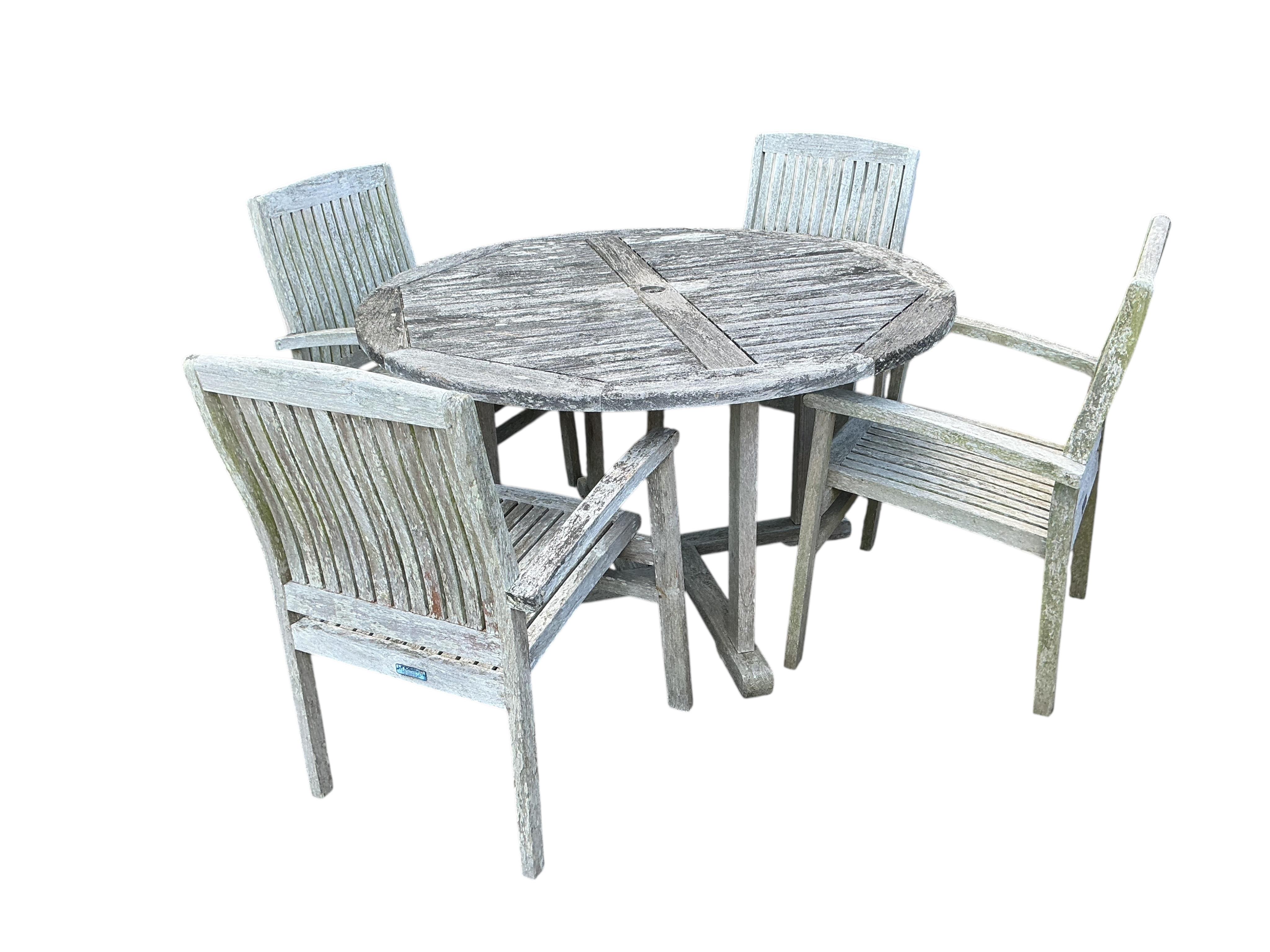 A Lindsey circular weathered teak garden table, diameter 130cm and four chairs